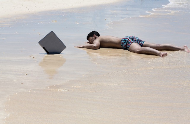 浜辺でパソコンと一緒に倒れる社畜人間